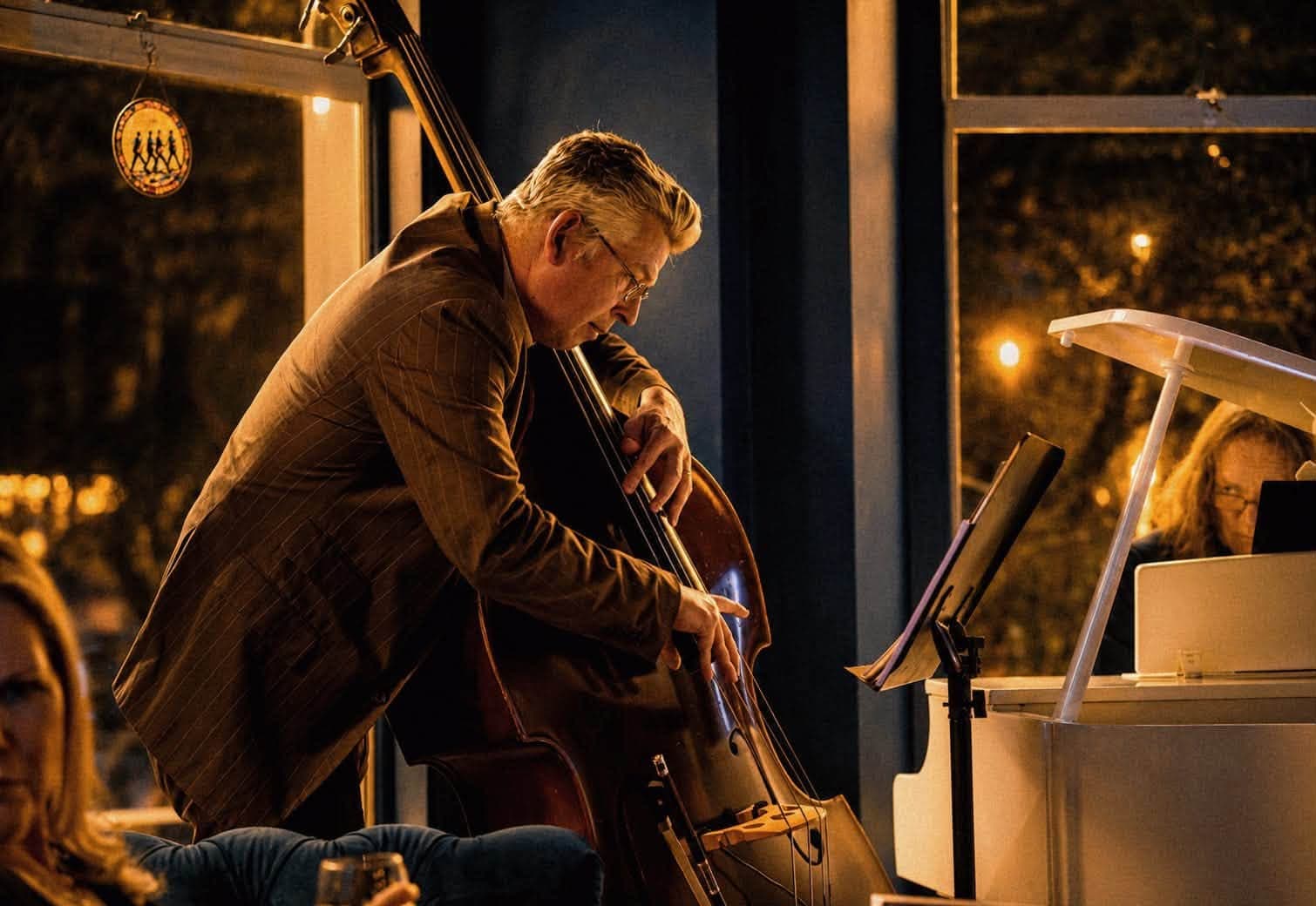A double bass player performing beside the white piano at Black Ivory